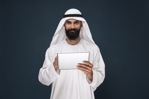 Арабский саудовский бизнесмен на синем фоне студии