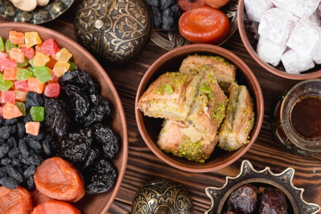 Arabian sweets for ramadan baklava; lukum and dried fruits on bowl over the desk