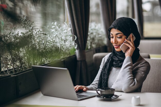 노트북에서 일하는 카페 안에 히잡에 아라비아 여자