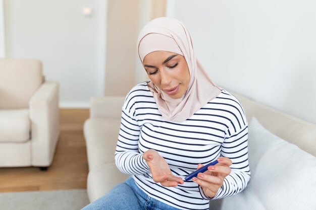 居間で自宅で血糖値テストをしているアラビアのイスラム教徒の女性