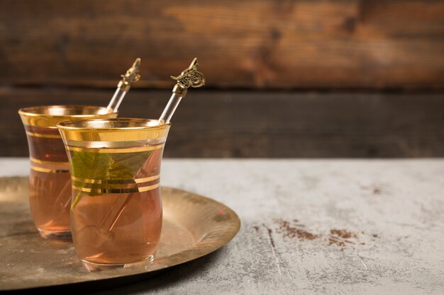 Арабский чай в стакане с зеленой мятой на подносе
