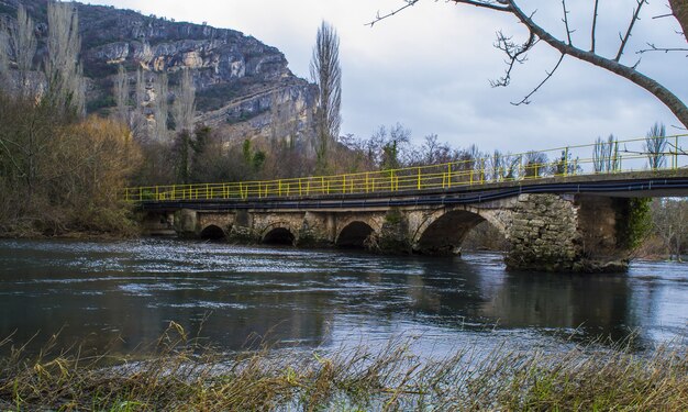 Арочный мост через реку в окружении скал в национальном парке Крка в Хорватии