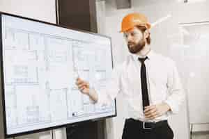 Free photo architect and engineer. man shows plan of building. tv screen.