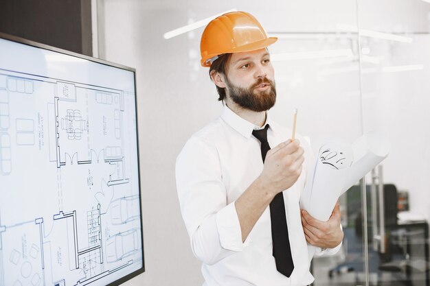 Architect and engineer. Man shows plan of building. TV screen.