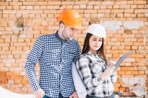 Architect in front of brick wall with clipboard