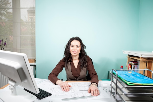 Architect at her working space with blueprints in front of her. Working on new projects. Architecture and design