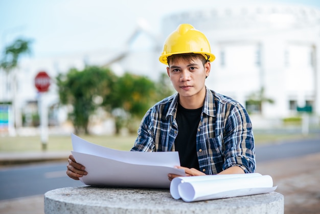 建築家は座って建築計画を調べました。