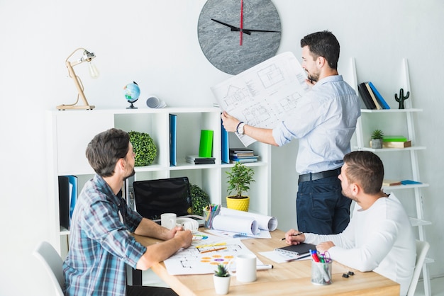 Free photo architect showing blueprint to his colleagues