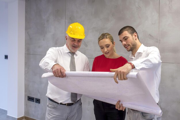 An architect showing plan of the new apartment to a young couple