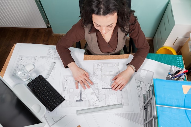 Женщина-архитектор за своим столом работает над чертежами. Бизнес и творчество. Архитектурная работа