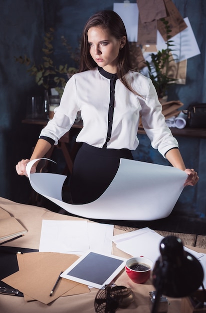 Foto gratuita donna dell'architetto che lavora al tavolo da disegno in ufficio oa casa. foto in studio studio
