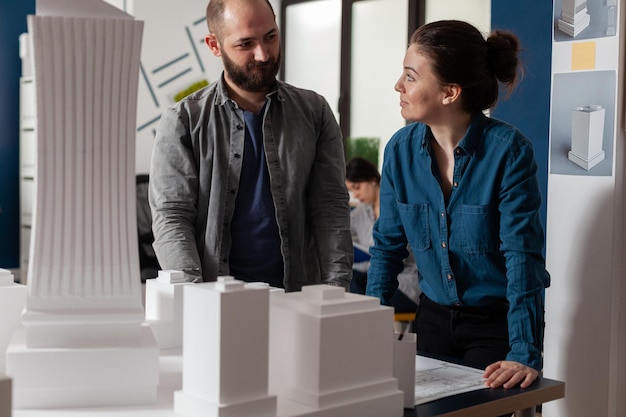 Architetti che fanno lavoro di squadra che si guardano l'un l'altro discutendo di progetti in un moderno ufficio di architettura. team di due colleghi architetti che lavorano insieme al progetto di pianificazione urbana.