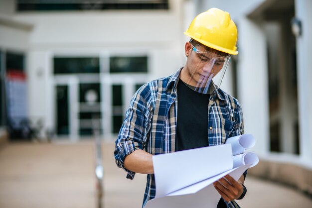 Architects hold the building plan and check the work.