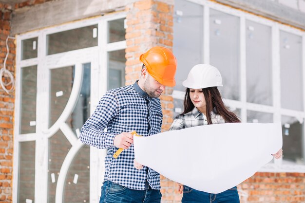 Architects looking at plan in front of house