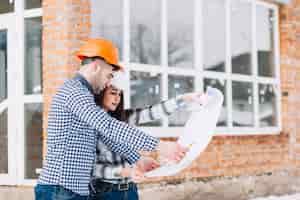 Free photo architects looking at plan in front of house