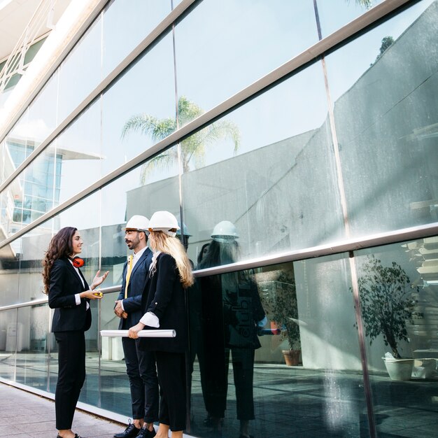 Architects wearing helmets talking in front of building