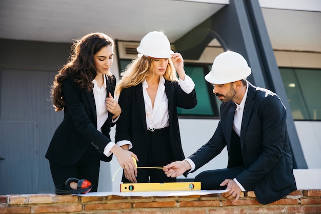 Free photo architects wearing helmets with level