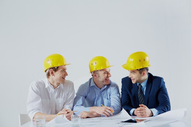 Architects with yellow helmets laughing