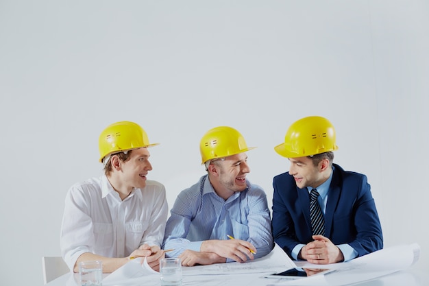 Architects with yellow helmets laughing