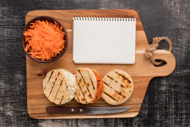 Arepas and notebook on wooden board