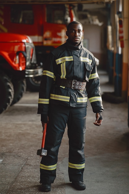 Арфиканский пожарный в форме. Человек готовится к работе. Парень с молотком.