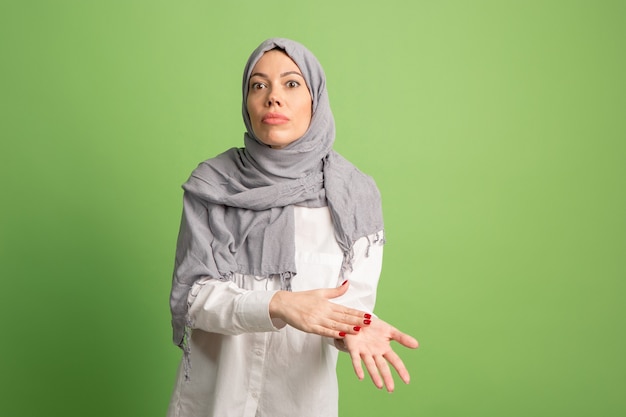Argue, arguing concept.arab woman in hijab. Portrait of girl, posing at green studio background. Young emotional woman. The human emotions, facial expression concept. Front view.