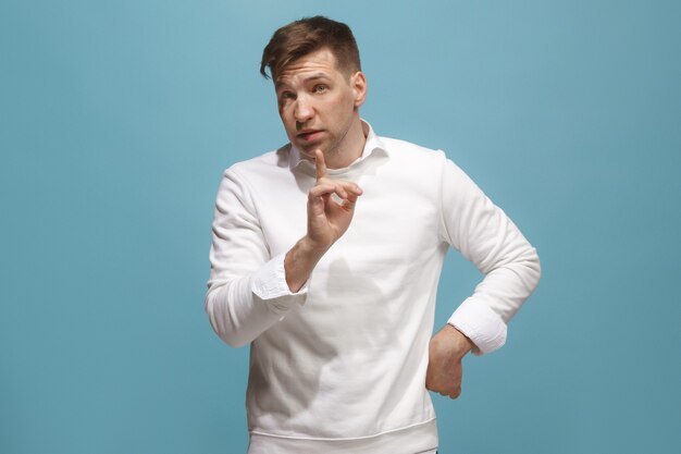 Argue, arguing concept. Beautiful male half-length portrait isolated on blue studio backgroud. Young emotional surprised man looking at camera. Human emotions, facial expression concept. Front view