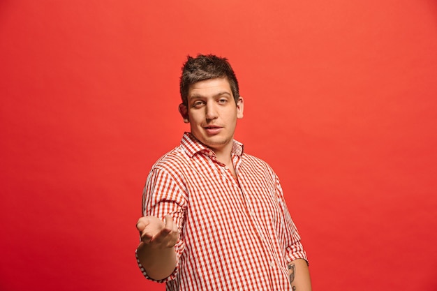 Argue, arguing concept. Funny male half-length portrait isolated on red studio backgroud. Young emotional surprised man looking at camera