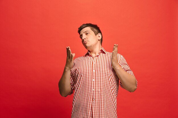 Argue, arguing concept. Funny male half-length portrait isolated on red studio background. Young emotional surprised man