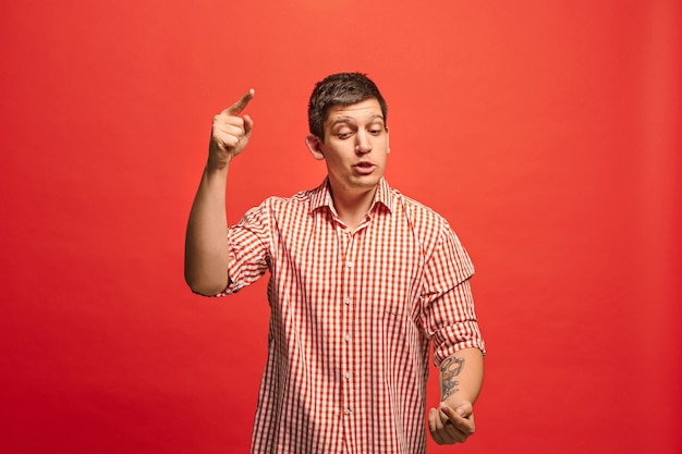 Argue, arguing concept. Funny male half-length portrait isolated on red studio background. Young emotional surprised man