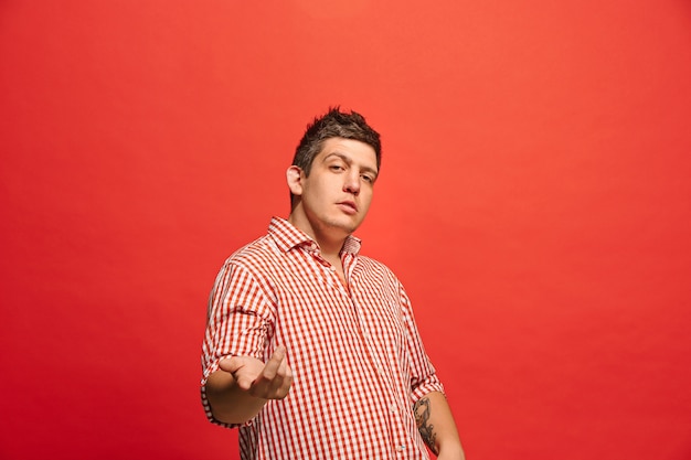 Argue, arguing concept. Funny male half-length portrait isolated on red. Young emotional surprised man