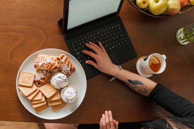 Arm on laptop with pastry top view