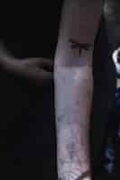 Foto gratuita braccio di donna con tatuaggio di libellula
