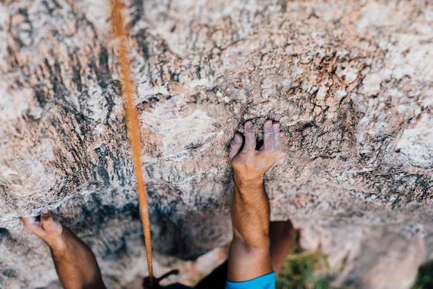 Arms and rope of rock climber