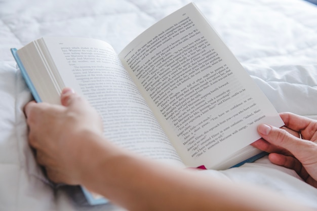 Arms with book on bed