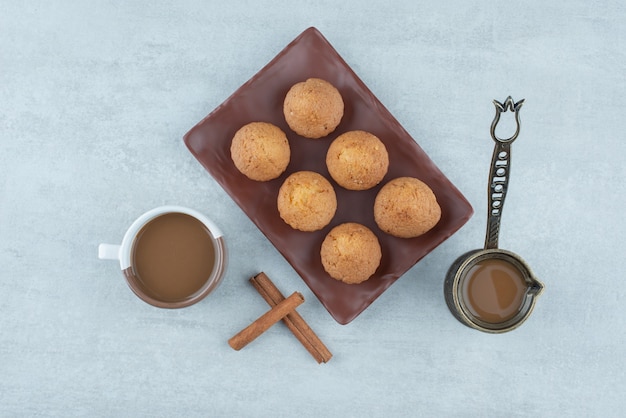 Foto gratuita aroma di caffè con bastoncini di cannella e cupcakes su sfondo bianco. foto di alta qualità