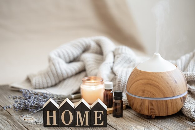 Aroma composition with modern aroma oil diffuser on wooden surface with knitted element, oils and candle