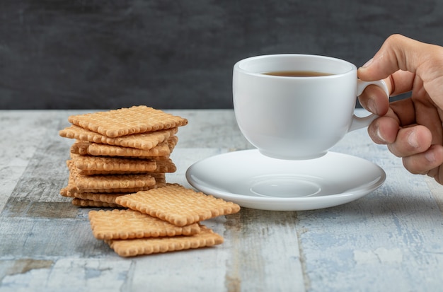 Aroma cup of tea with tasty crackers on a wooden table.