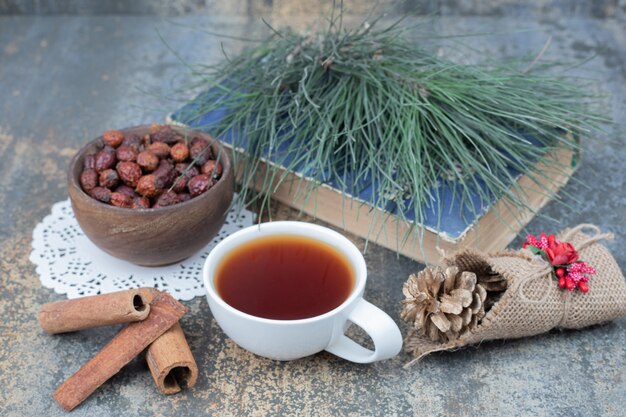 Aroma tea in white cup with cinnamon and pinecone on marble table