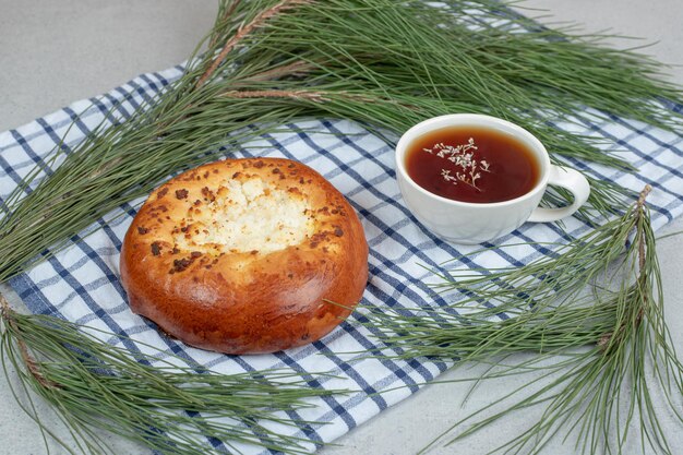 Aroma white cup of herbal tea with pastry on tablecloth.