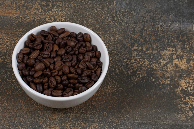 Aromatic coffee beans in white bowl.