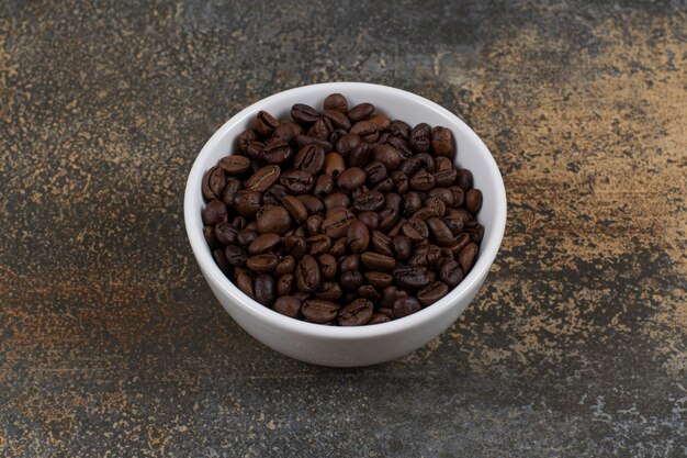 Aromatic coffee beans in white bowl.