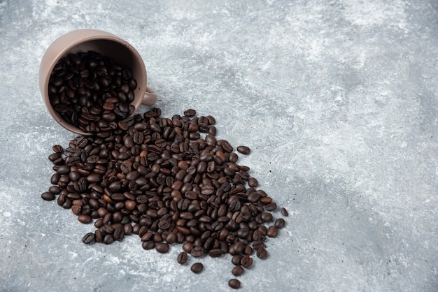 무료 사진 대리석 표면에 컵에서 향기로운 볶은 커피 콩.