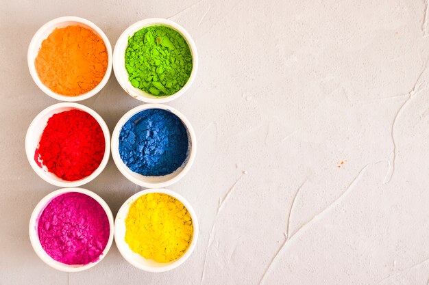 Arranged bowls of holi color powder on concrete backdrop