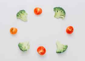 Free photo arranged halved broccoli and cherry tomatoes in circular frame isolated on white background