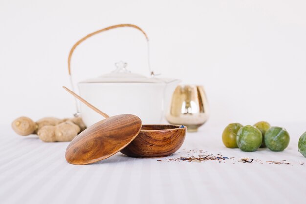 Arranged teapot with plums and utensils