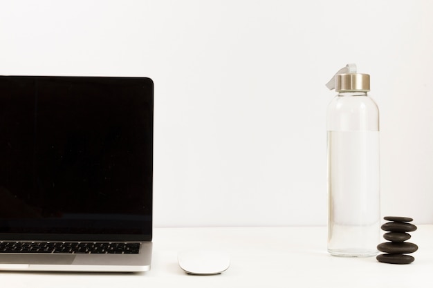 Arranged work space with laptop and water bottle on desk 