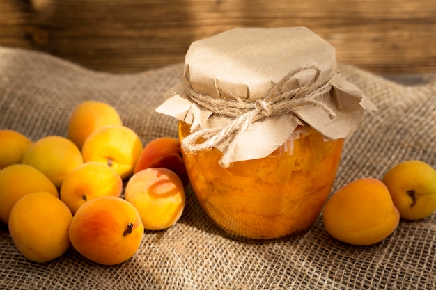 Arrangement of apricots on cloth with jar of compote