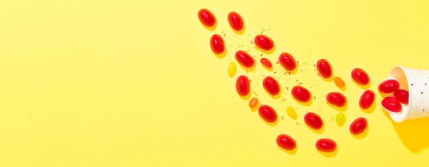 Arrangement of candies on yellow background with copy space