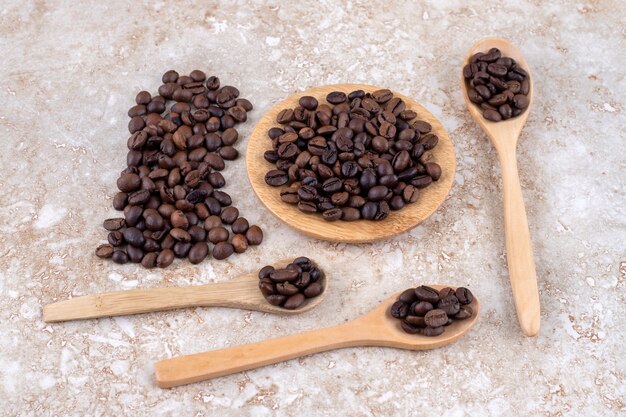 An arrangement of coffee beans on spoons, a trivet and a small pile 